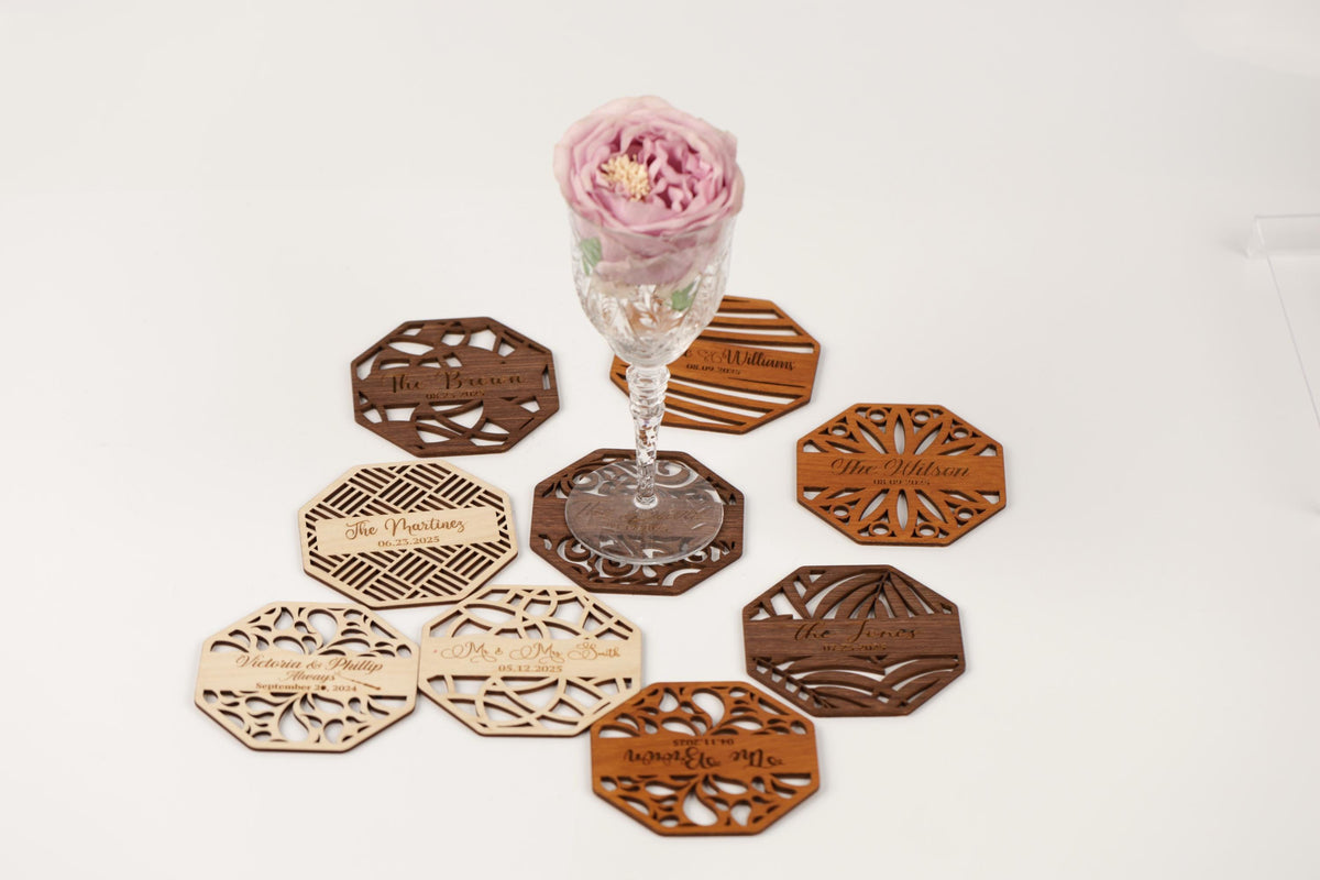 a glass vase with a pink flower, surrounded by various coasters and wooden coasters with text on them.
