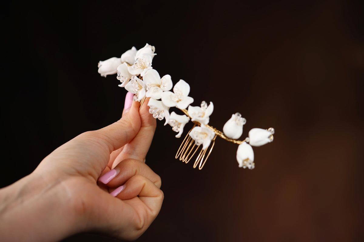 a hand holding a white flower and a comb