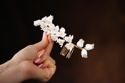 a hand holding a white flower and a comb