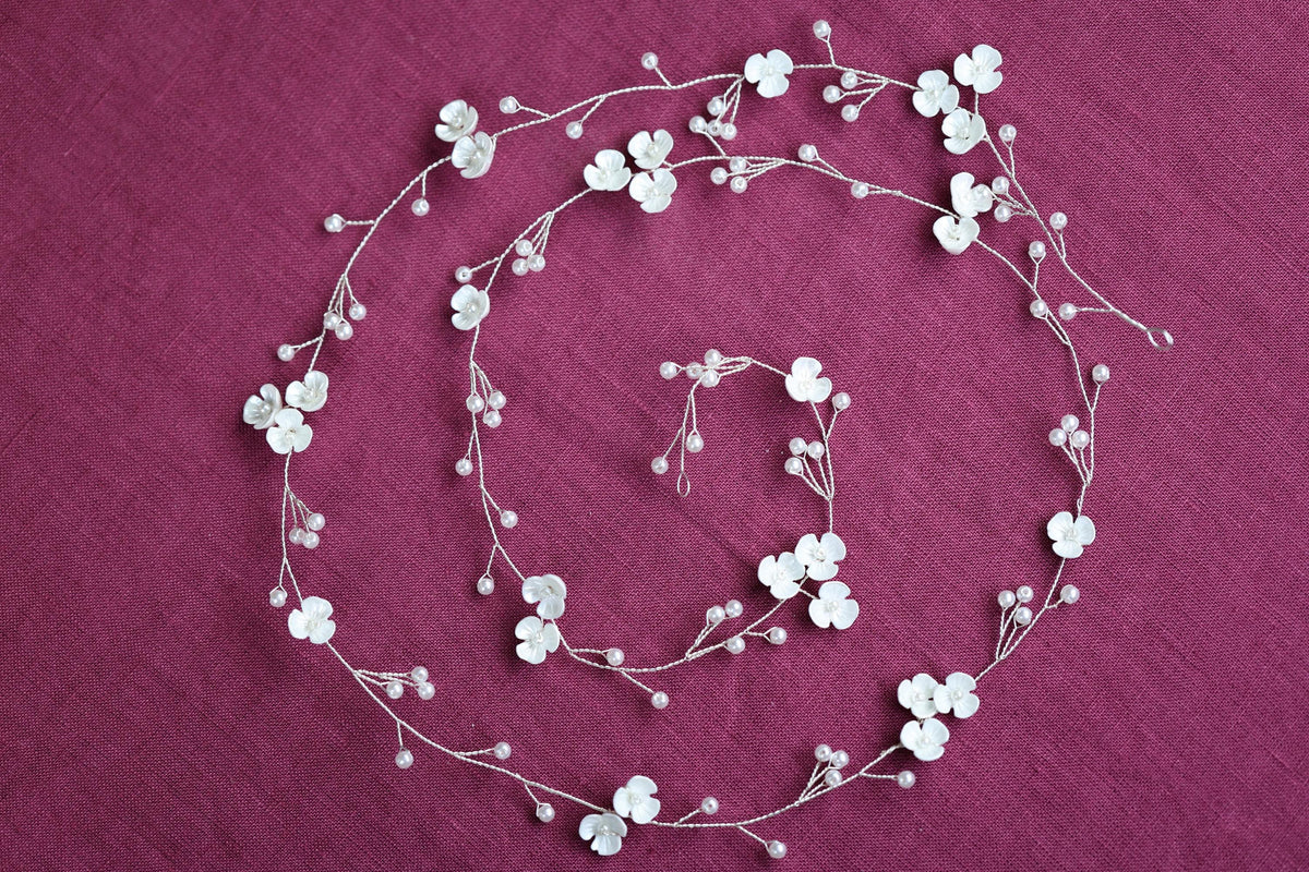 a white flower headband on a pink background