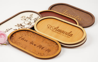 a collection of oval-shaped wooden trays with personalized engraved names and phrases on them.