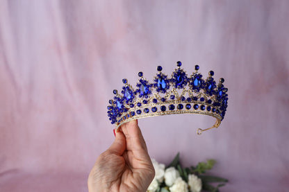 a hand holding a blue beaded bracelet next to a purple flower