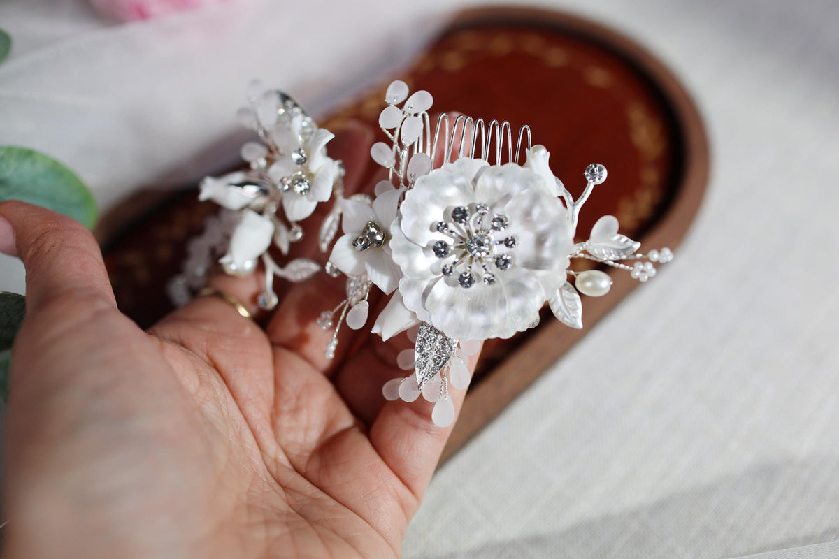 a person is holding two white flowers in their hand