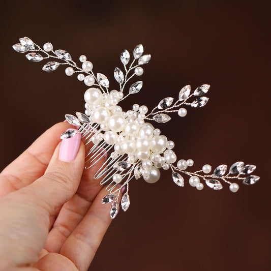 a woman holding a hair comb with pearls and leaves on it