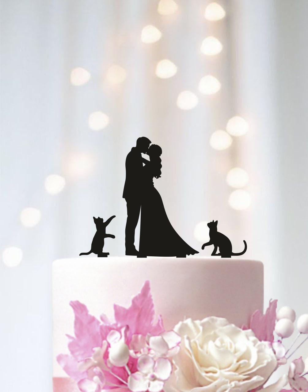a wedding cake with a silhouette of a bride and groom and a cat