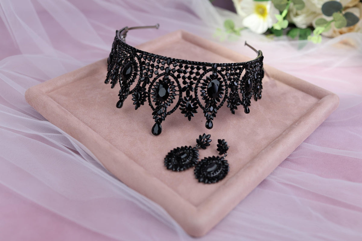 a black tiara and earrings on a pink tray