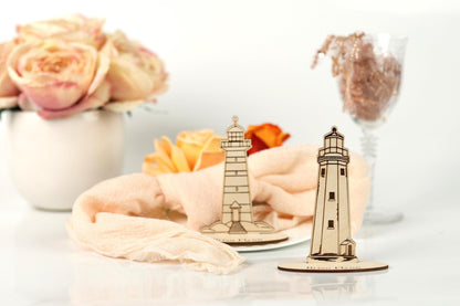 a white vase with pink roses, a wooden lighthouse, and a glass vase with a bouquet of flowers, all placed on a white surface.