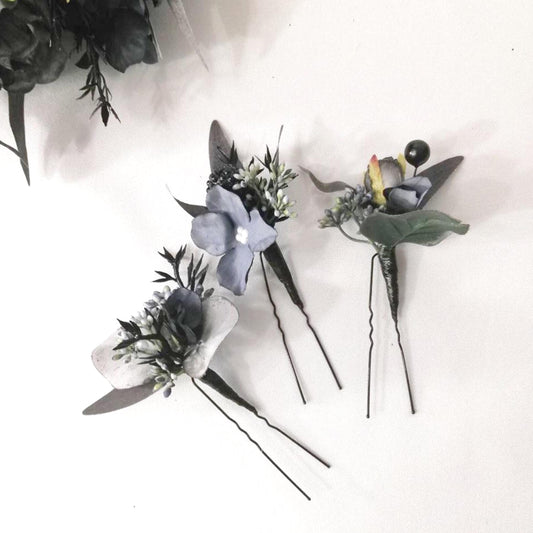 a collection of three floral hair clips, each adorned with a different flower, resting on a white surface.