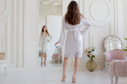 a woman in a white robe standing in front of a mirror