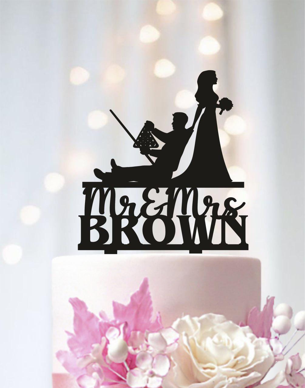 A silhouette of a man and a woman on a cake topper, with the text "Mr & Mrs Brown" below them.