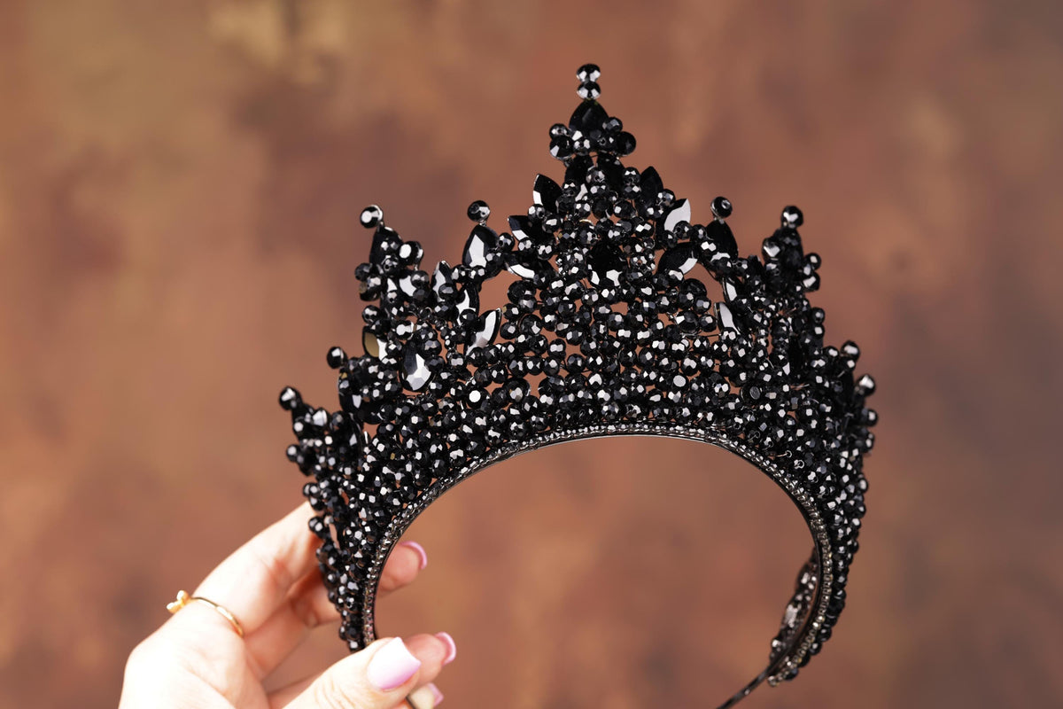 a woman is holding a black tiara in her hand