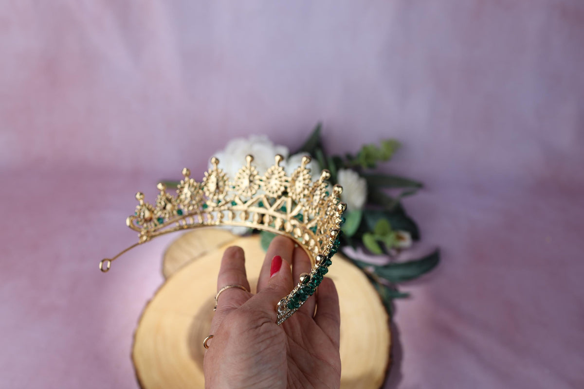a woman's hand holding a tiara on top of a wooden plate