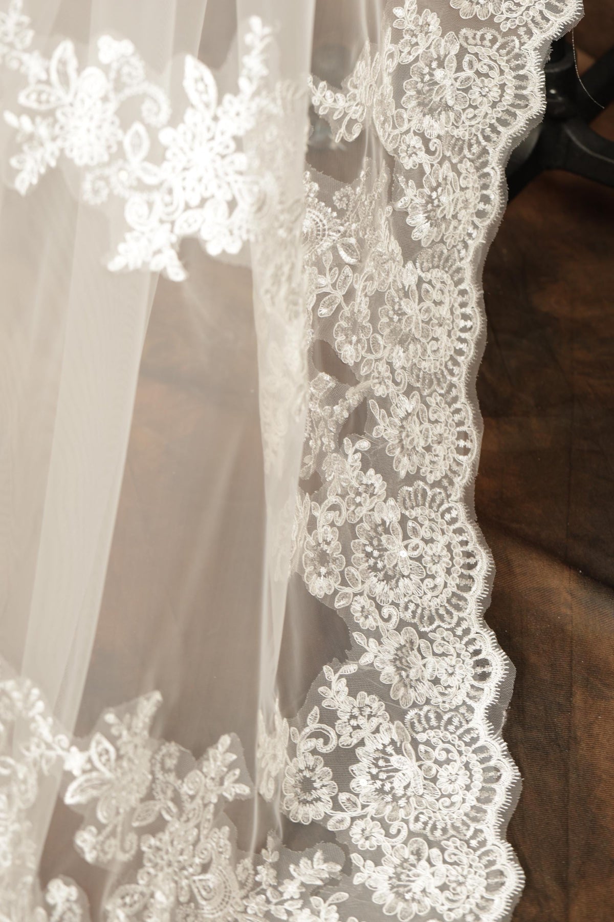 A close-up view of a delicate, white lace fabric with intricate floral embroidery.