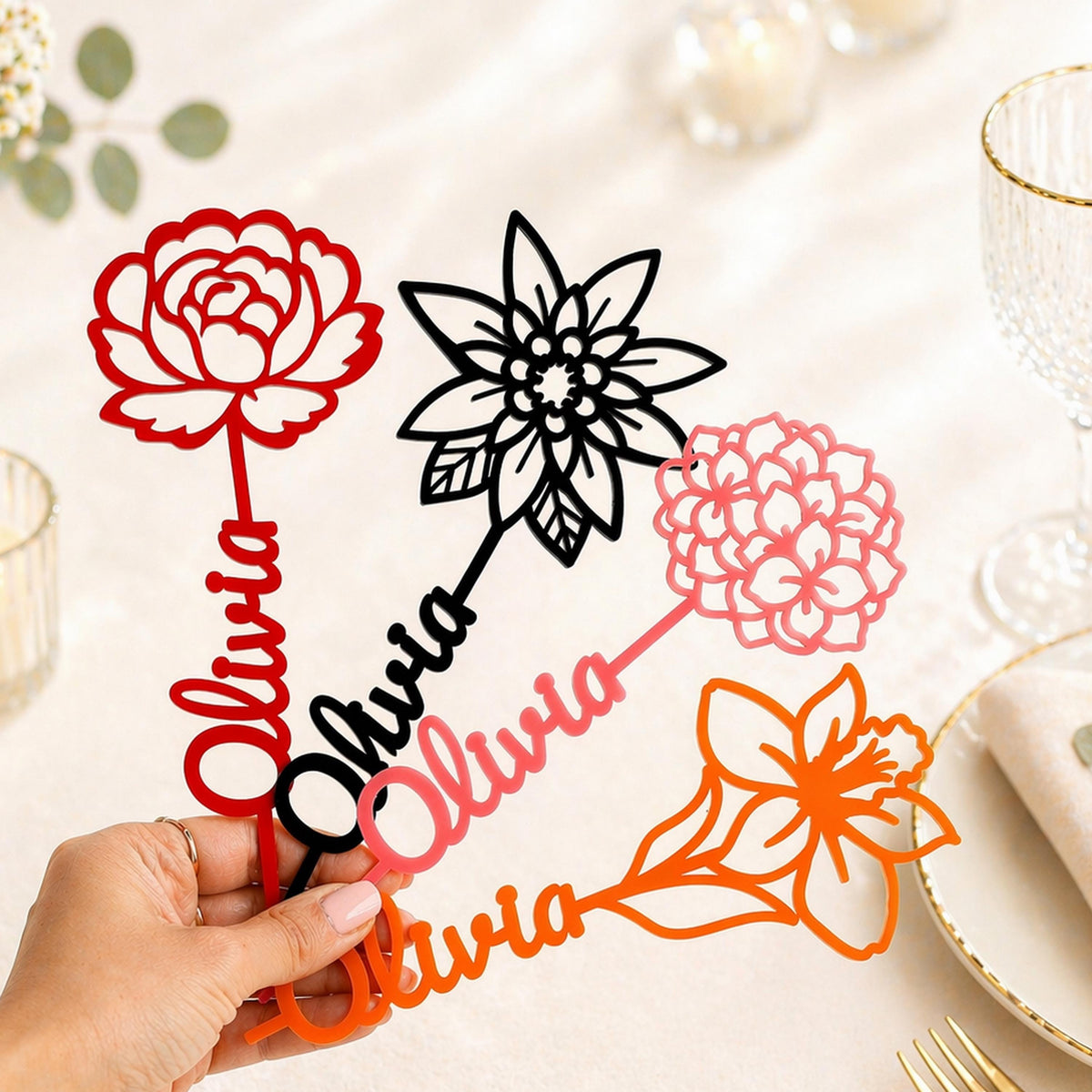 A hand holding a set of colorful name spoons with floral designs on them.