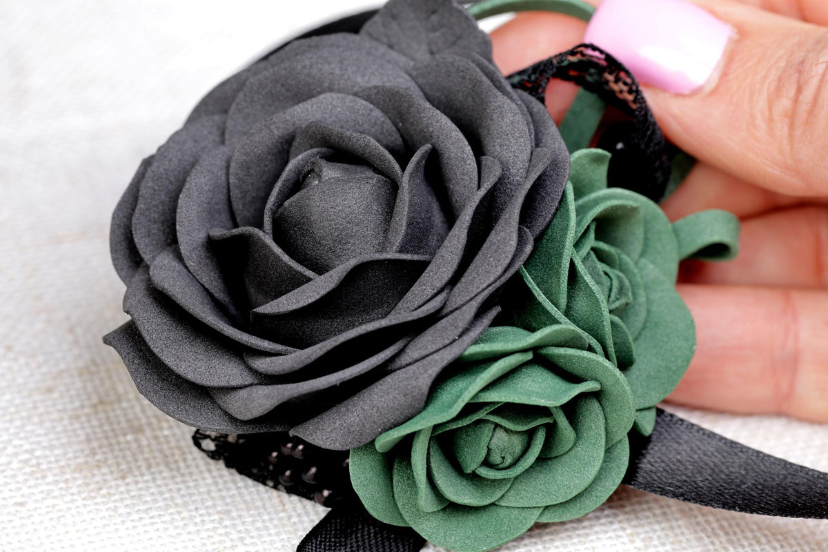 a hand holding a black flower on a white cloth