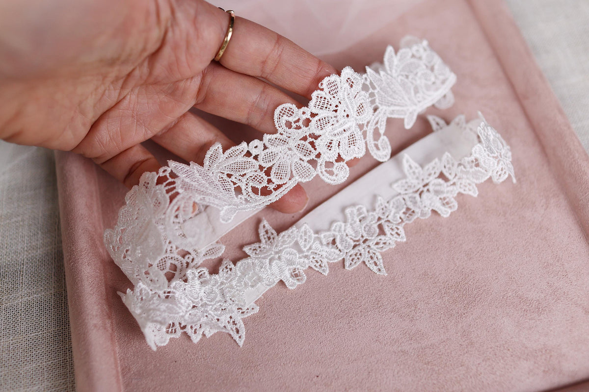 a pair of white lace garters being held by a woman