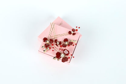 A pink box with red and gold floral decorations on top, including a hair clip and a small box with a similar design.
