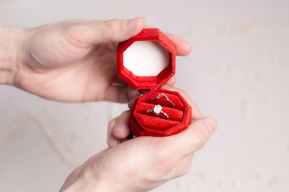 a person holding a red ring with a diamond in it