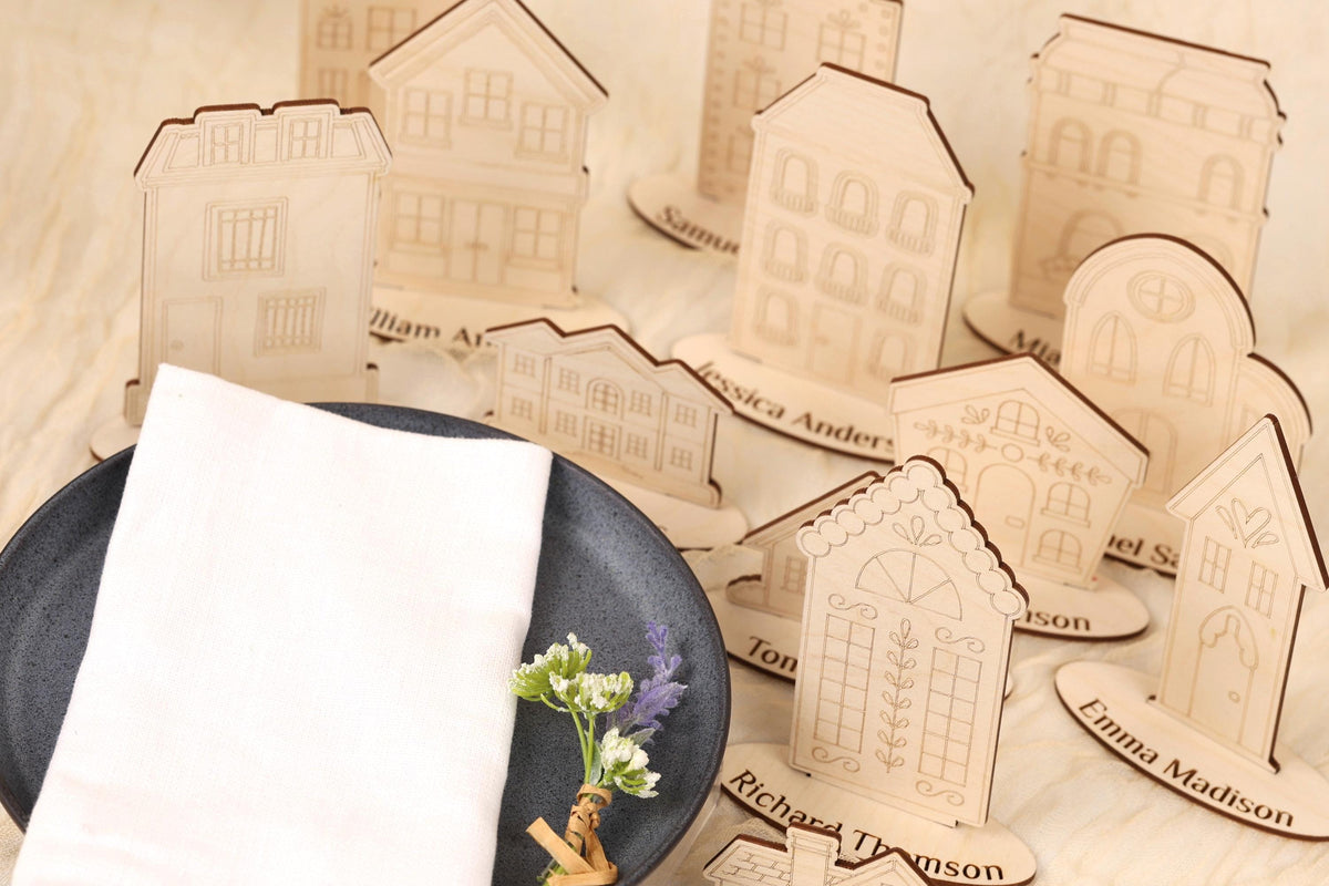 a collection of wooden place cards with names on them, placed on a table next to a white napkin and a small floral arrangement.