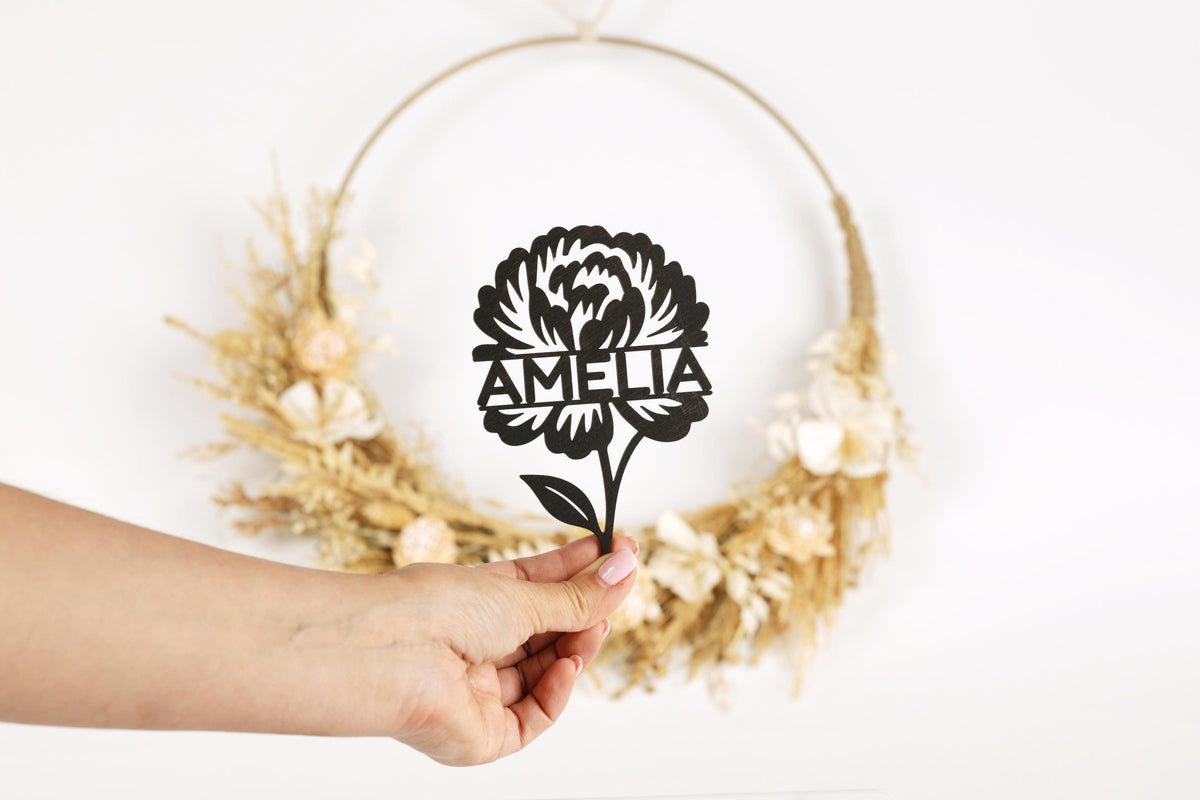 A hand holding a paper cutout of a flower with the name "Amelia" written on it.
