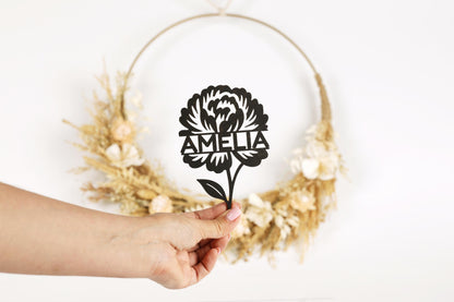 A hand holding a paper cutout of a flower with the name "Amelia" written on it.