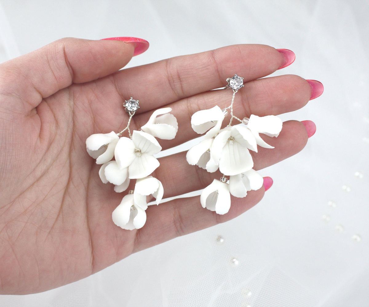 a woman's hand holding three white flowers