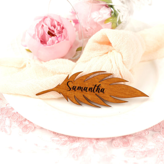 A wooden nameplate with the name "Samantha" engraved on it, placed on a white plate. The nameplate is surrounded by a pink flower and a white napkin.