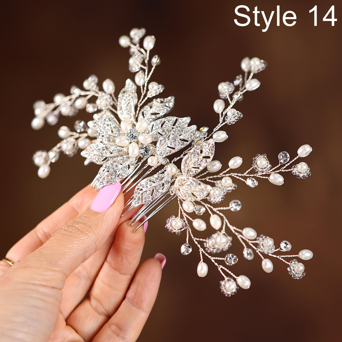 A hand holding a decorative hair accessory with intricate silver and white embellishments, including leaves and pearls.