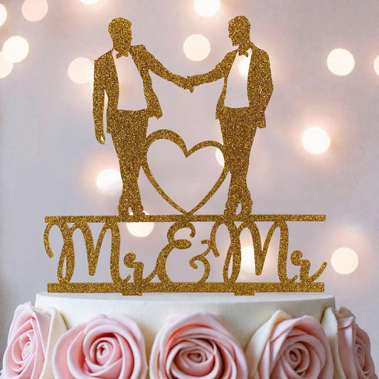 A gold glitter wedding cake topper with the words "Mr & Mrs" on it, featuring two silhouetted figures of a man and a woman holding hands and a heart.