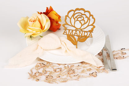 a table setting with a white plate, a wooden nameplate, and a bouquet of yellow and orange roses.