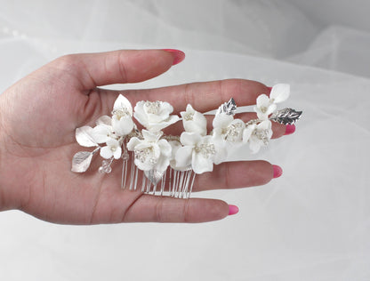 a woman's hand holding a white flower comb