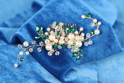 A decorative hair accessory with white and green beads, pearls, and a gold comb, resting on a blue fabric background.