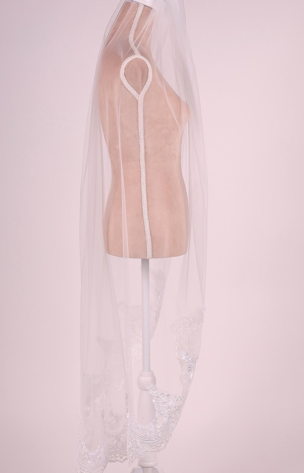 A mannequin wearing a white veil with a lace trim.