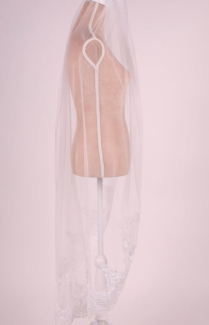 A mannequin wearing a white veil with a lace trim.