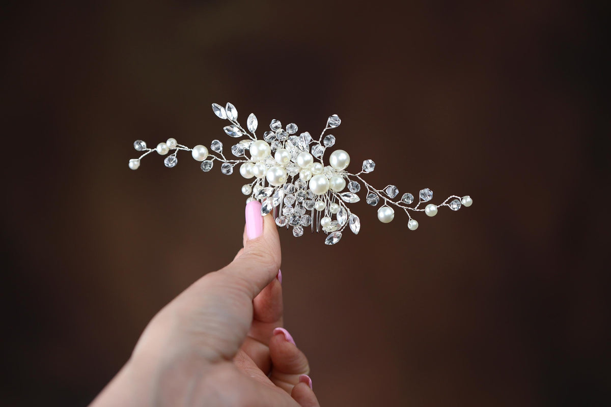 a woman is holding a crystal and pearl hair comb