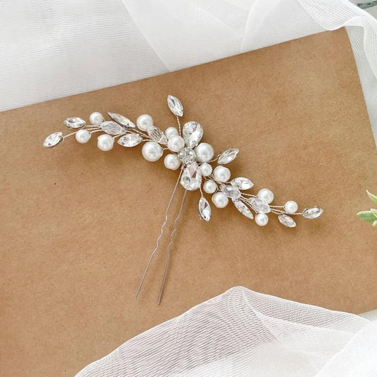 A decorative hair clip with a floral design and sparkling crystal elements is placed on a brown surface.