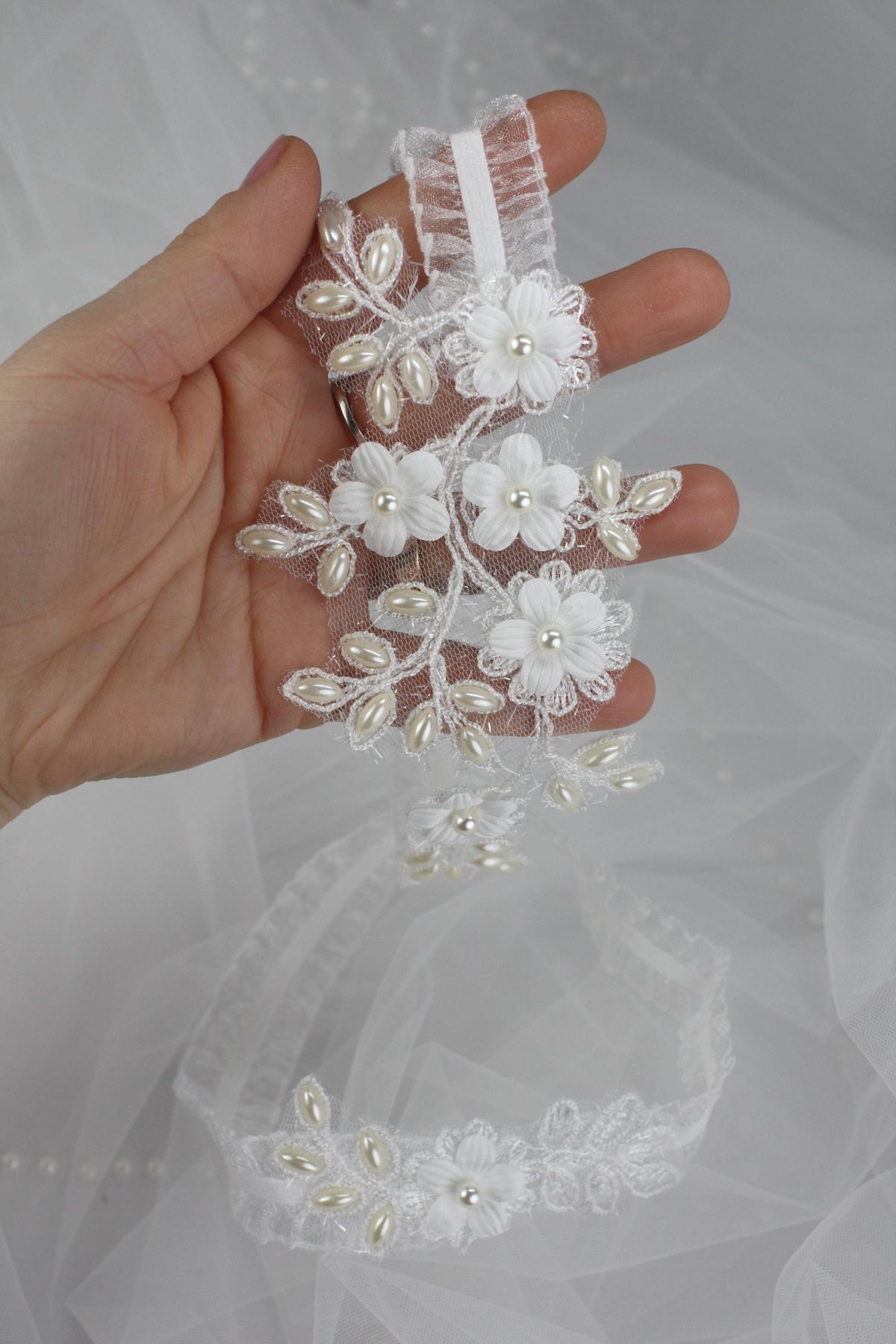 a hand holding a piece of wedding garter