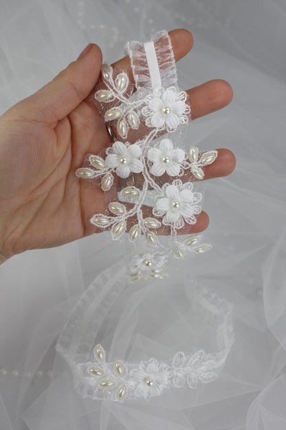 a hand holding a piece of wedding garter