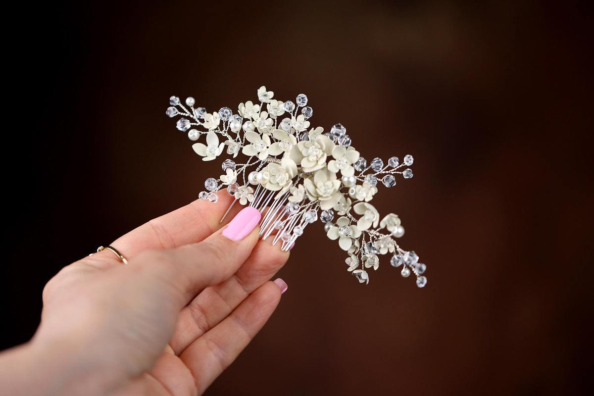 a hand holding a white flower and crystal hair comb