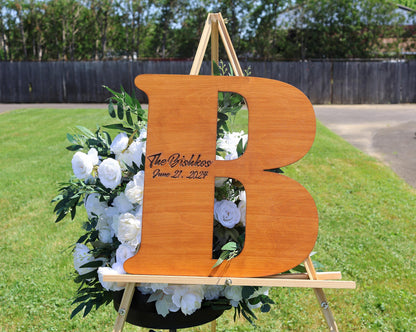 a wooden letter 'B' with a floral arrangement in the background.