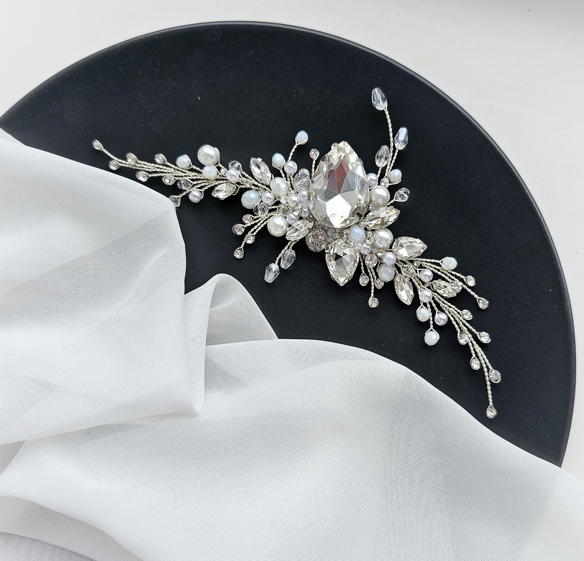 a black plate topped with a white cloth and a crystal brooch