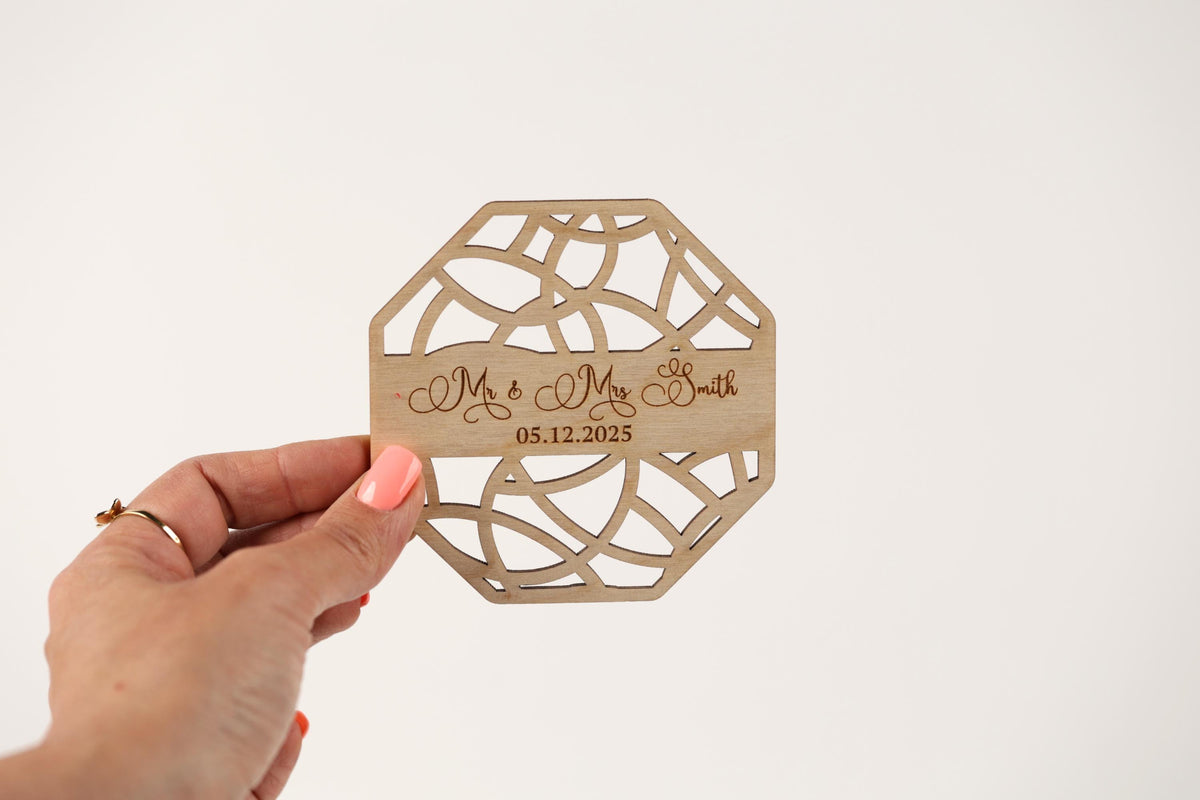 A hand holding a wooden coaster with the names 'Mr & Mrs Smith' and the date '05.12.2025' printed on it.