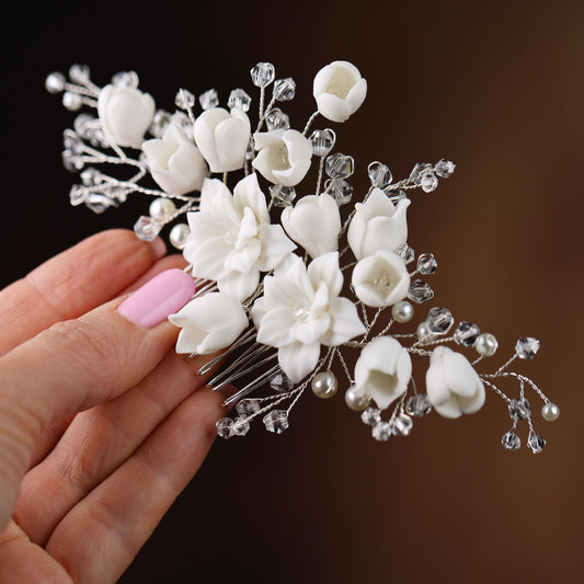 a hand holding a white flower and crystal hair comb