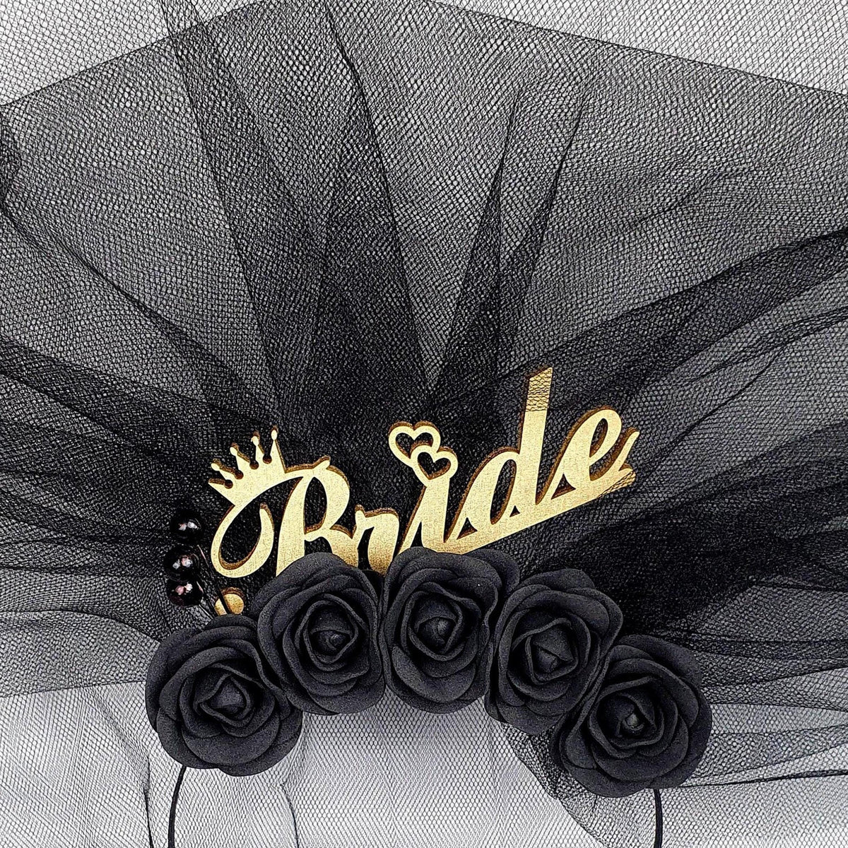 a black veil with a gold crown and the word "Bride" written on it, along with black roses.