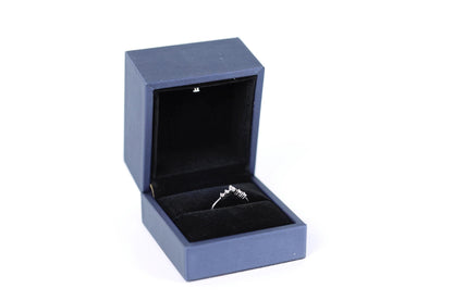 A blue jewelry box containing a silver ring.