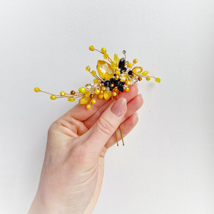 a hand holding a yellow and black hair comb