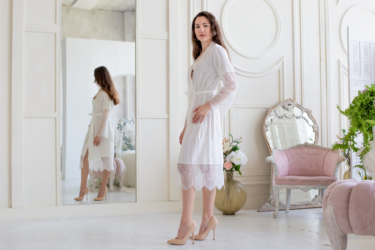 a woman in a white dress standing in front of a mirror