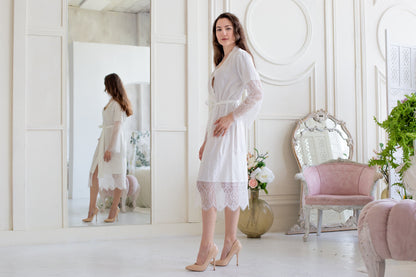 a woman in a white dress standing in front of a mirror