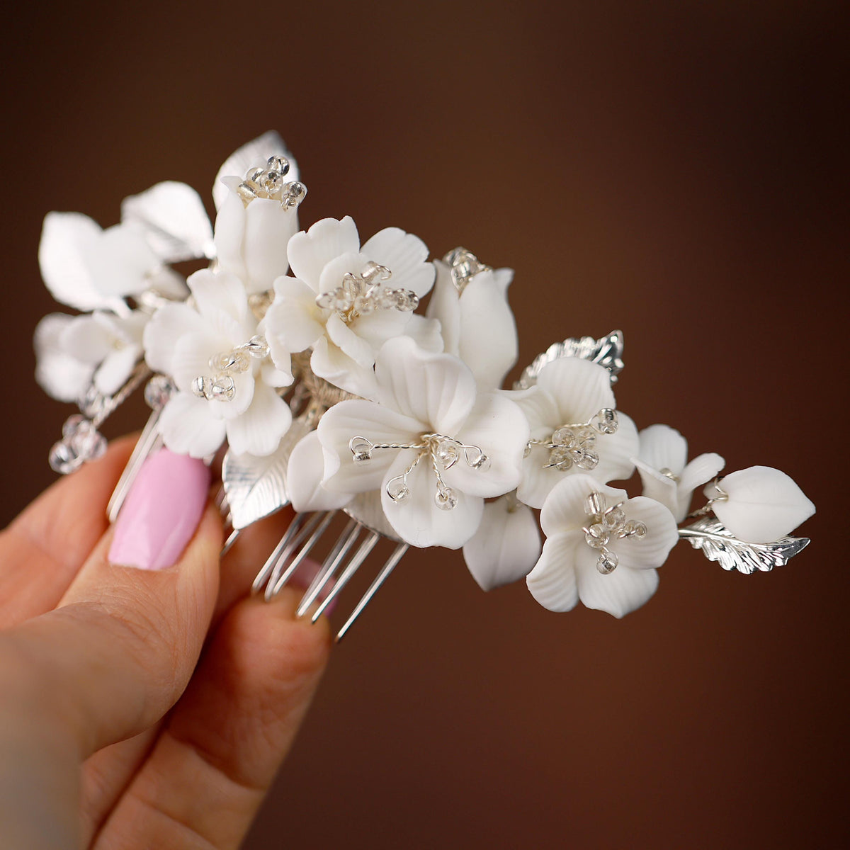 a hand holding a white flower and a hair comb