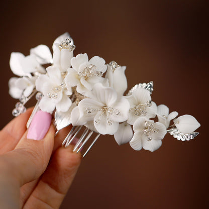 a hand holding a white flower and a hair comb